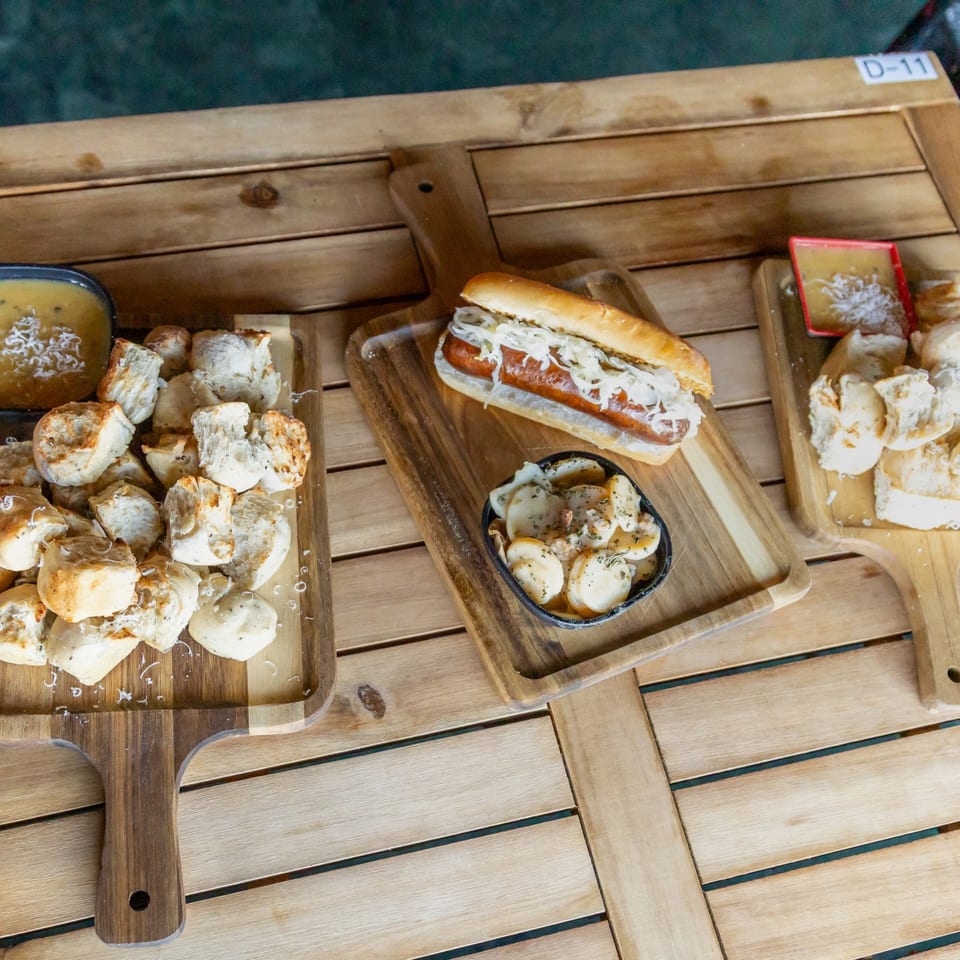 Brat, potato salad and bread bites on serving boards